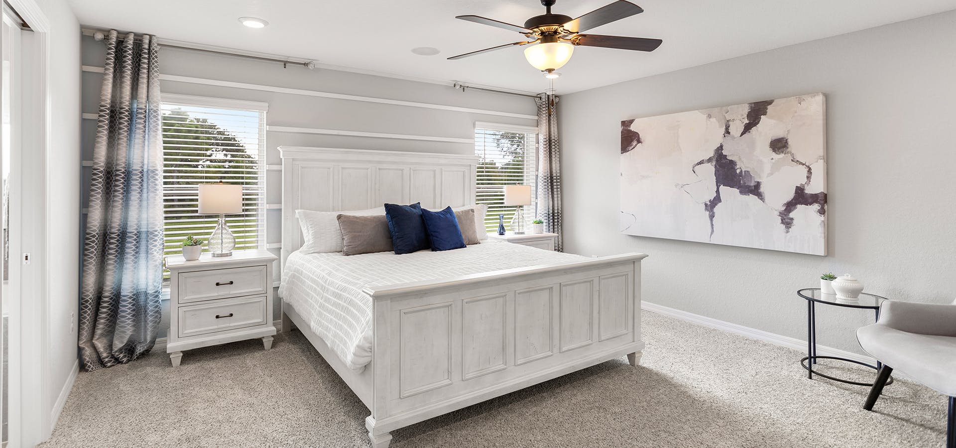 Big bedroom with coastal white furniture and lots of light streaming in