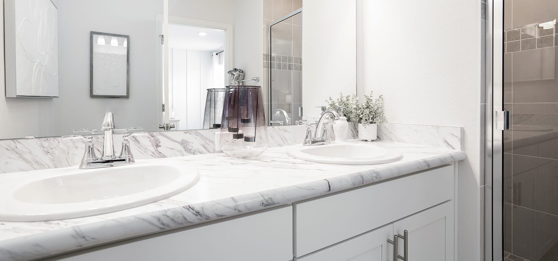 Large bathroom vanity with white cabinets and glass-enclosed shower