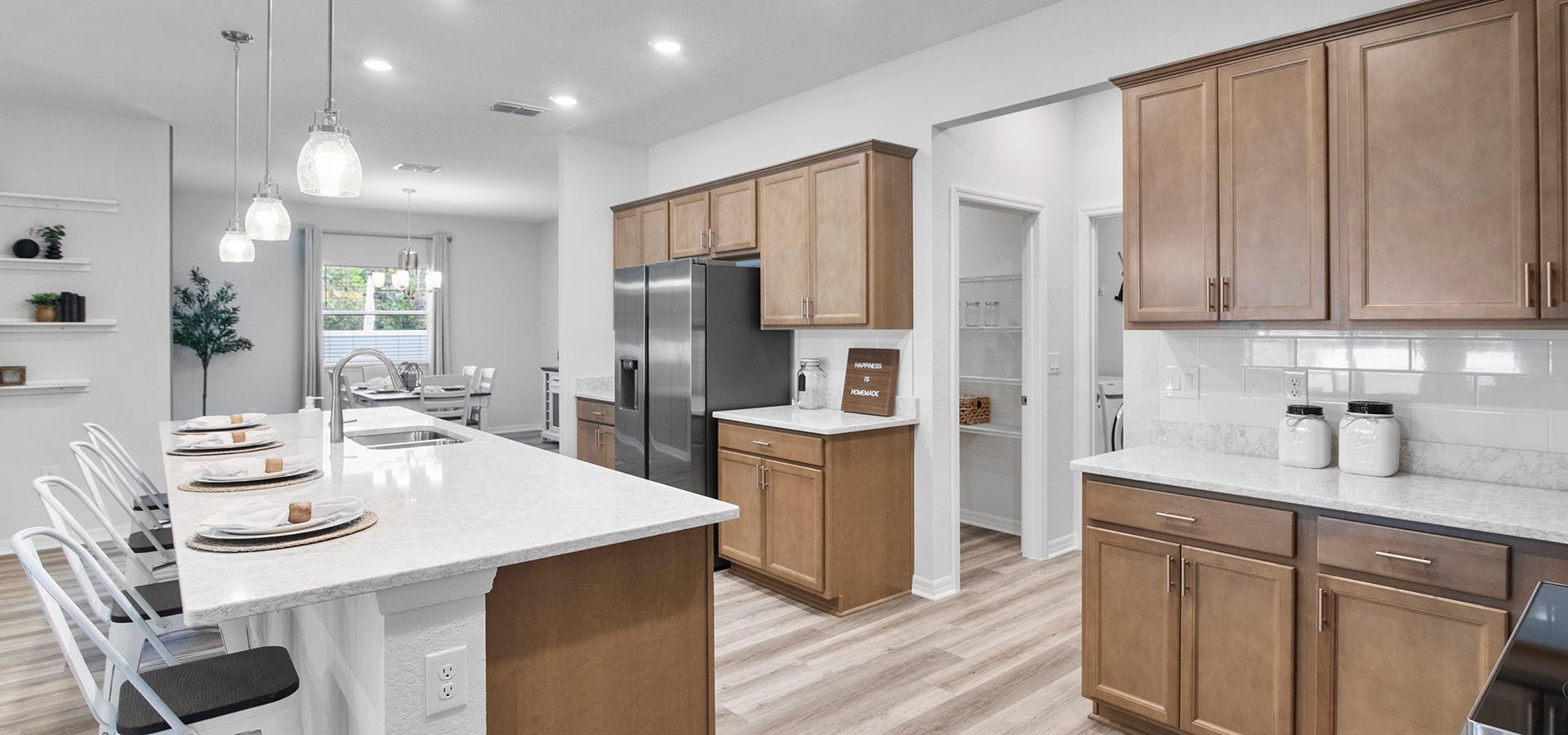 Open kitchen with wood cabinets, wood floors, and a large island with seating.