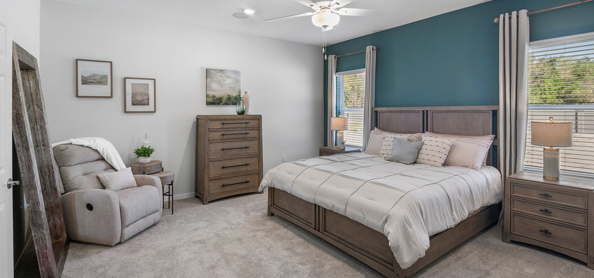 Large primary bedroom suite with a king bed, armchair, and teal accent wall,