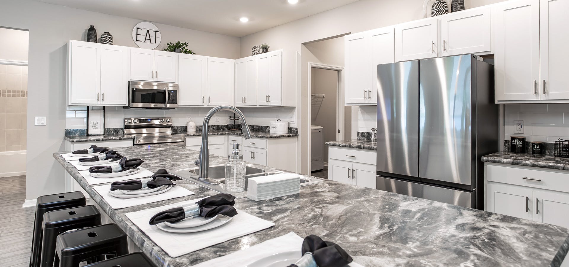 Large kitchen with white cabinets, stone-look countertops, and a large island