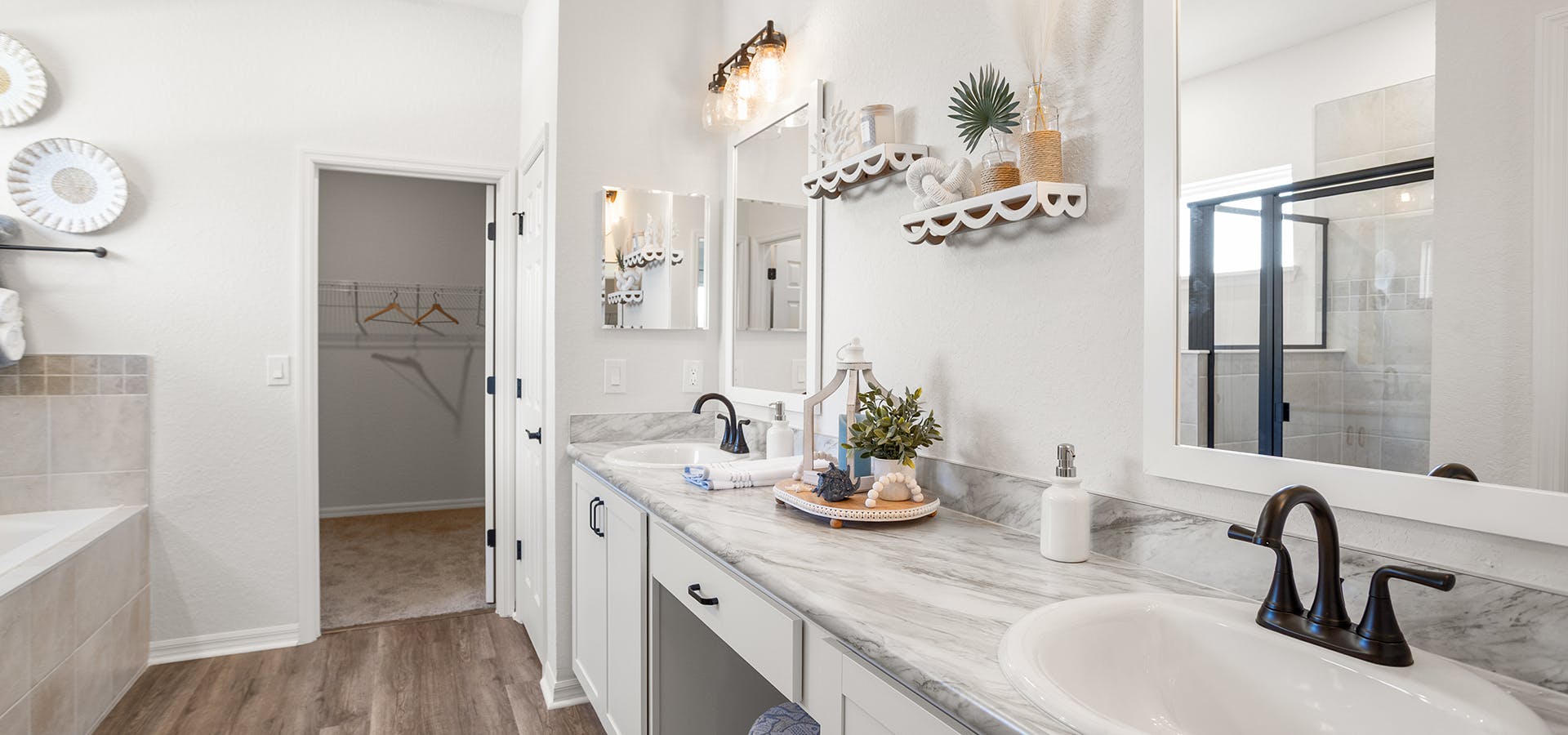 Large en-suite bathroom with dual vanities, a soak tub, framed mirrors, and black fixtures