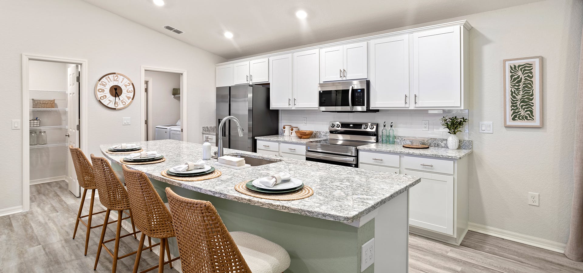 Bright open kitchen in the Parker by Highland Homes, with a large island, granite, and white cabinets.