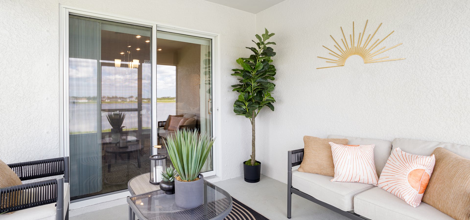 A covered lanai with a sofa, chairs, and sunshine