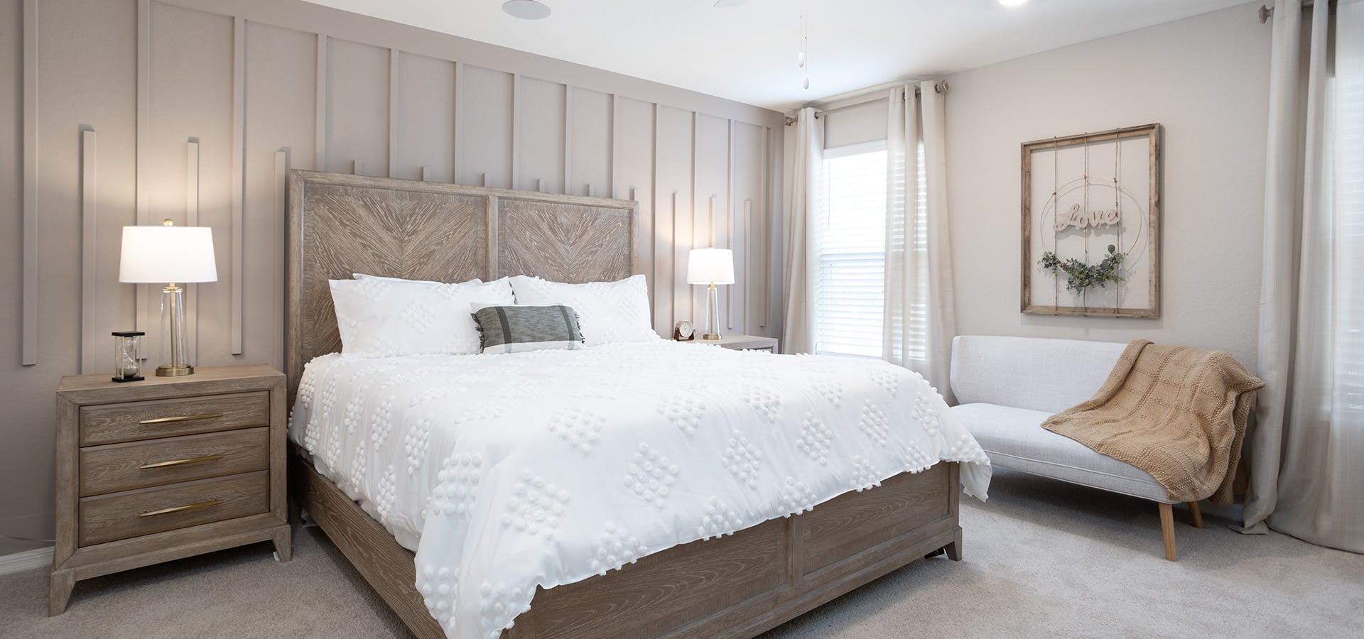 Large bedroom with natural woods, white linens, and loveseat