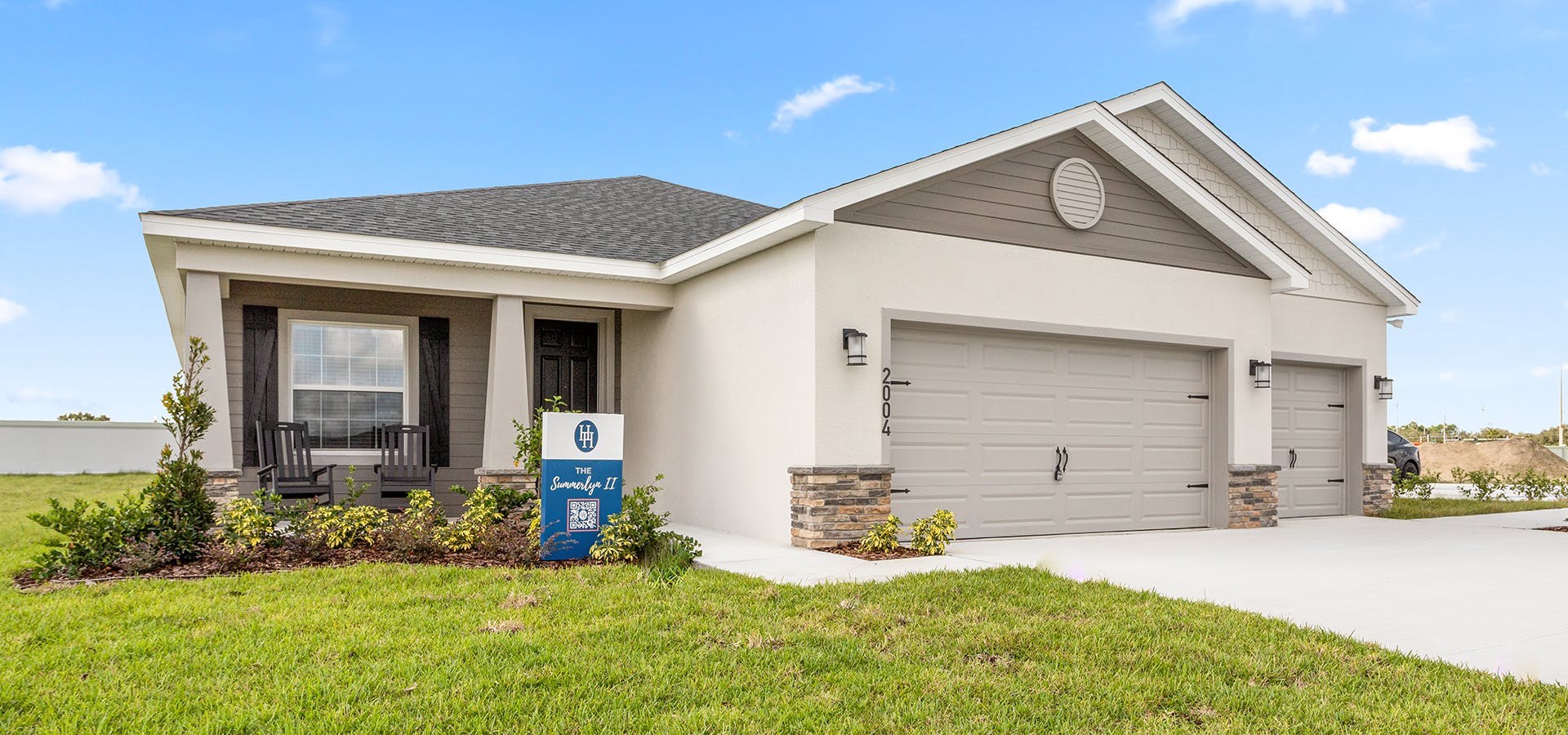Exterior of the Summerlyn II by Highland Homes, featuring a 3-car garage, a columned front porch, and stone exterior accents,