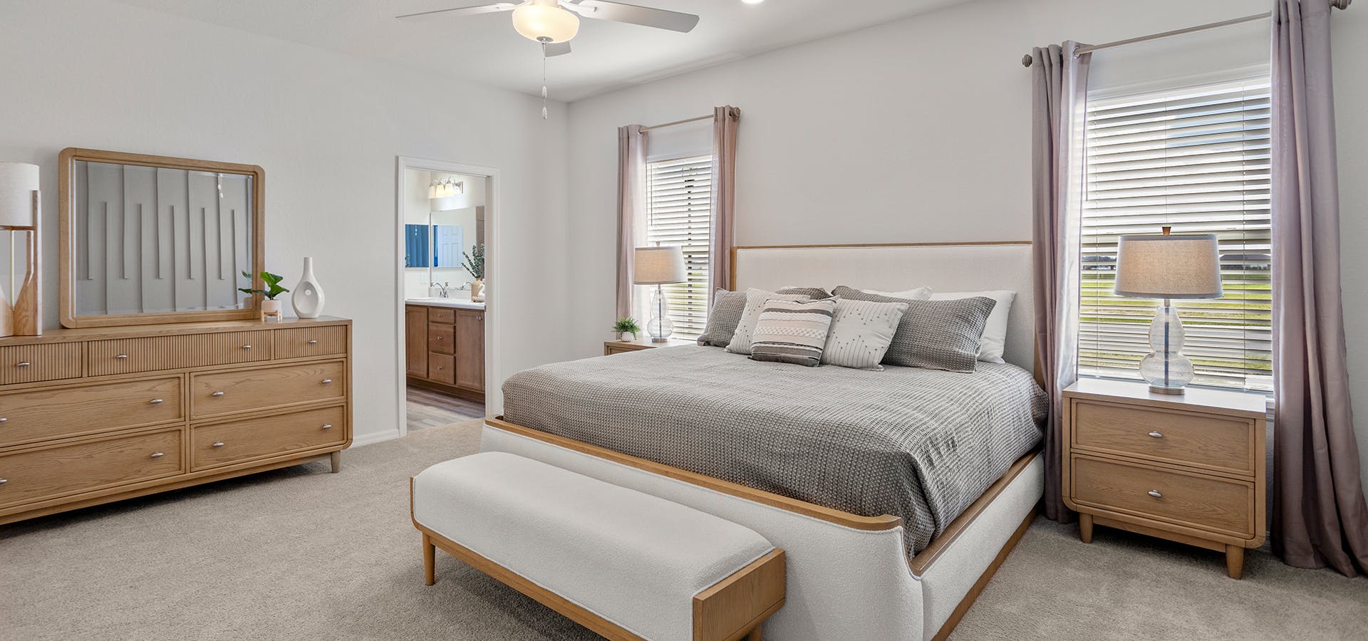 Large primary bedroom with mid-century style furniture in a Florida new construction home