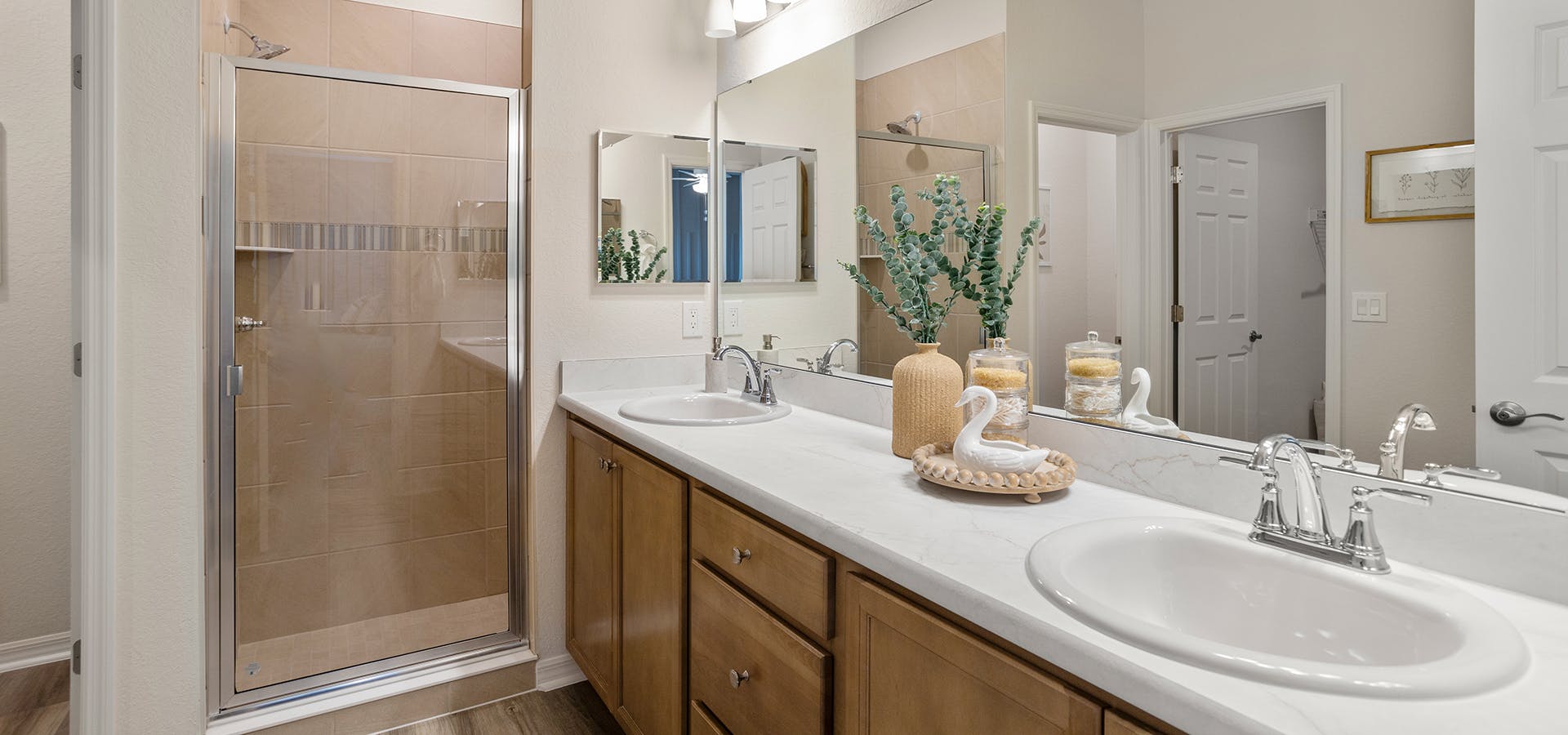 Large primary bathroom with dual vanities and a tiled shower