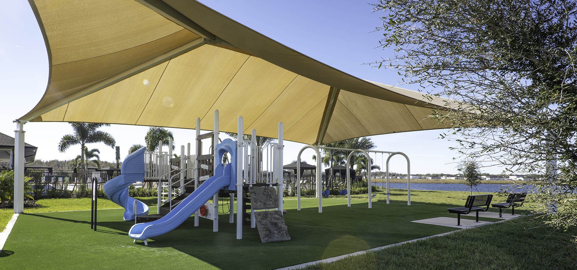 Shaded neighborhood playground with benches at Cypress Ridge Ranch