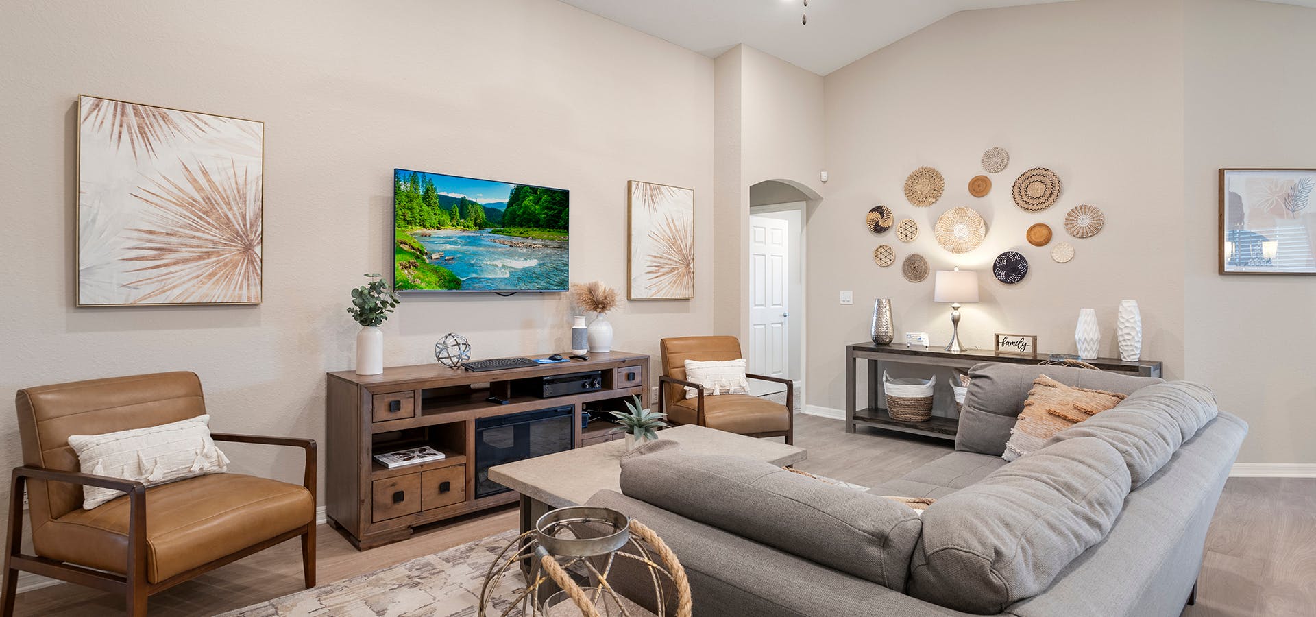 Sofa and two chairs centered around a large TV and fireplace console