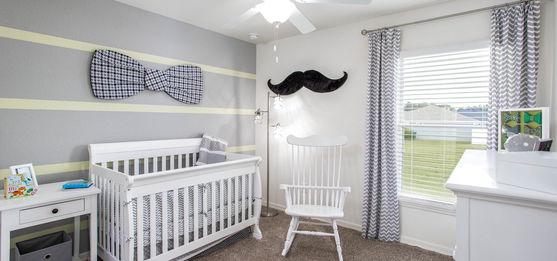 Baby's room with a striped accent wall and white nursery furniture