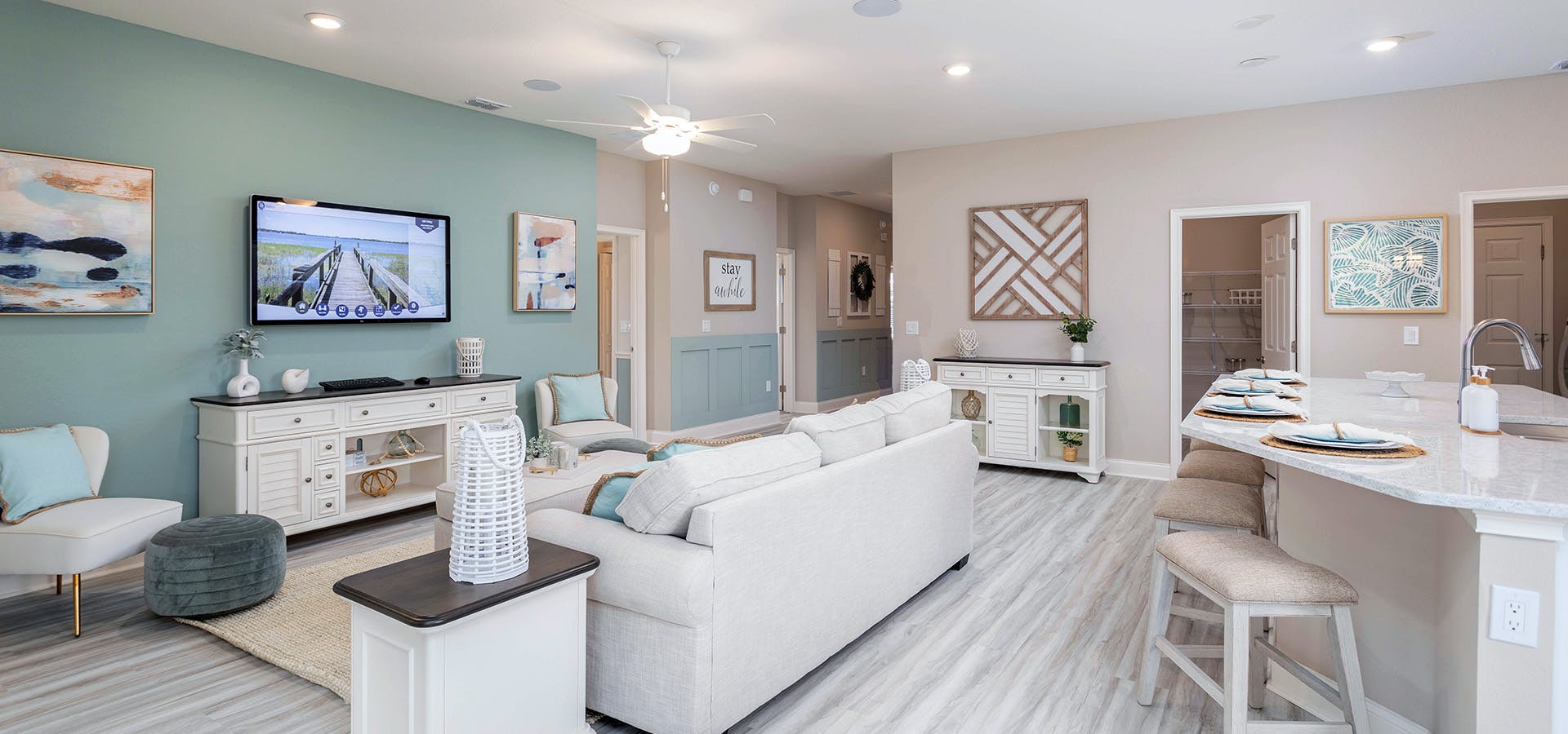 Living room with light colored wood flooring and furniture. and a mint green accent wall