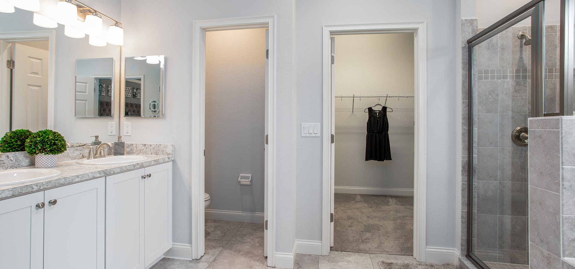 Bathrooms with dual vanities, a large shower, and adjacent closet