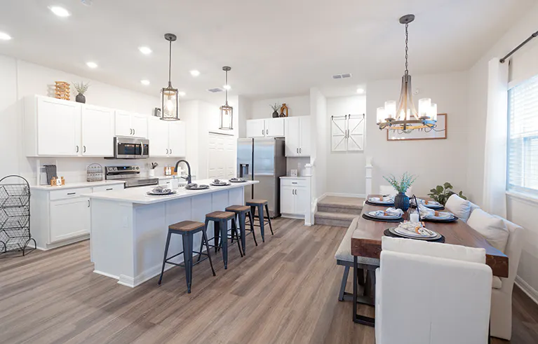 Bungalow kitchen in St. Cloud, FL with wood flooring, white cabinets, and table and island dining spaces.