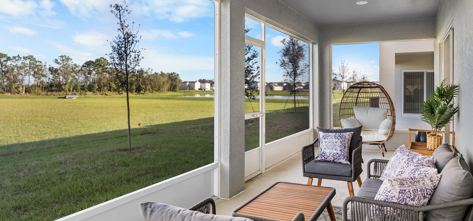 Large screened lanai in the Wesley II by Highland Homes, looking out into a sunny backyard and greenbelt.