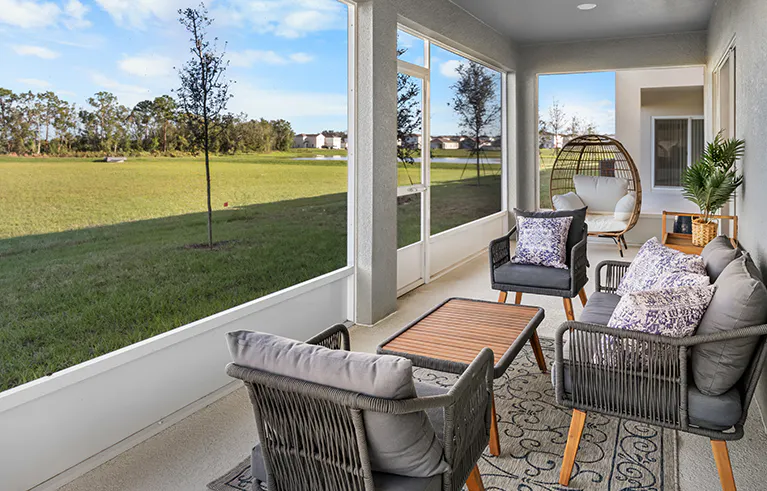 Large screened lanai in the Wesley II by Highland Homes, looking out into a sunny backyard and greenbelt.