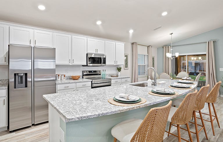 A bright, open kitchen with white cabinets and a large island, in a Winter Haven, Florida, new construction home.