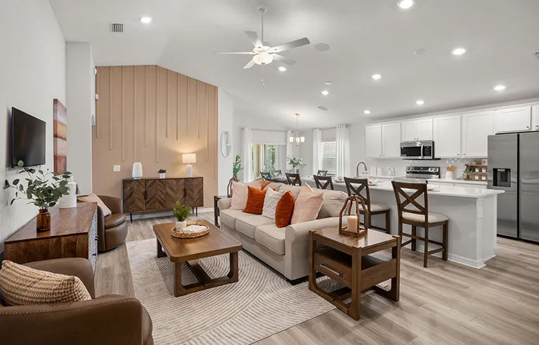 Parker by Highland Homes open living area featuring an accent wall with vertical trim, overstuffed sofa, and MCM console table, open to the kitchen with white finishes.