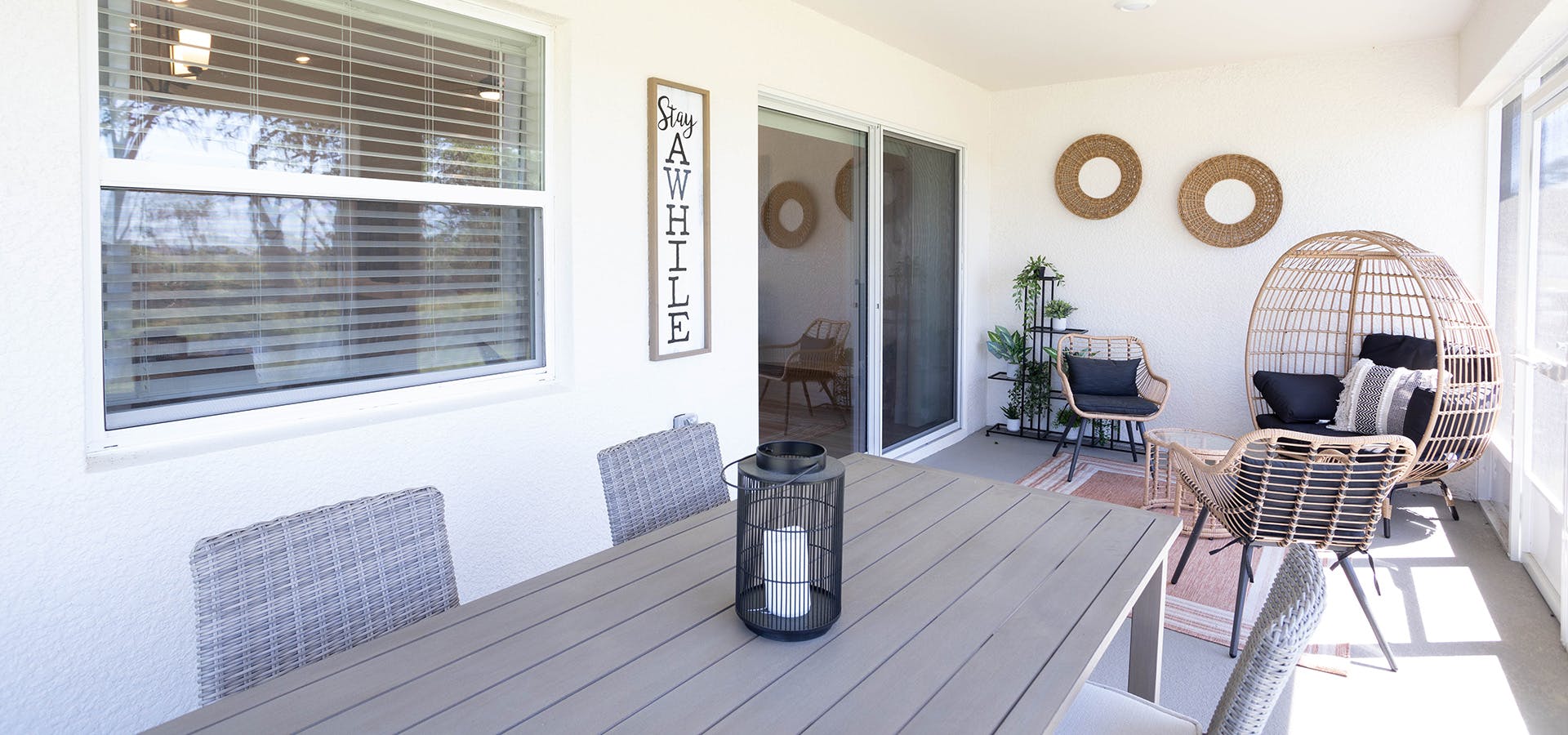 A large screened lanai on a Florida new construction home, with an outdoor table and wicker papasan chair.