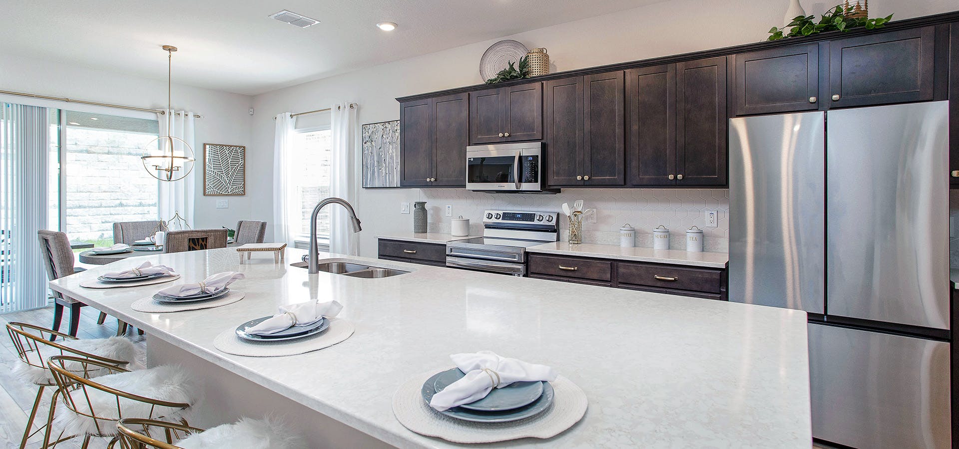 Kitchen with a large island, wood cabinets, quartz counters, and bright brass accents adding a glam decor touch.