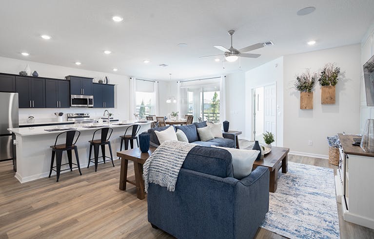 Living area in the Shelby by Highland Homes, with wood floors, blue cabinets, and overstuffed furniture.