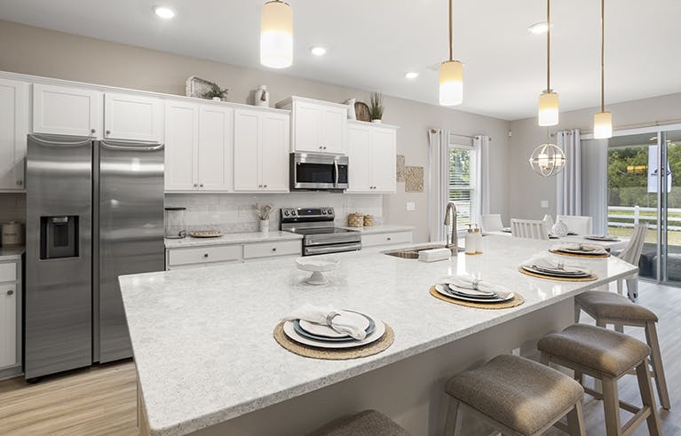Bright, open kitchen with white cabinets and quartz, a large island, and adjacent dining.