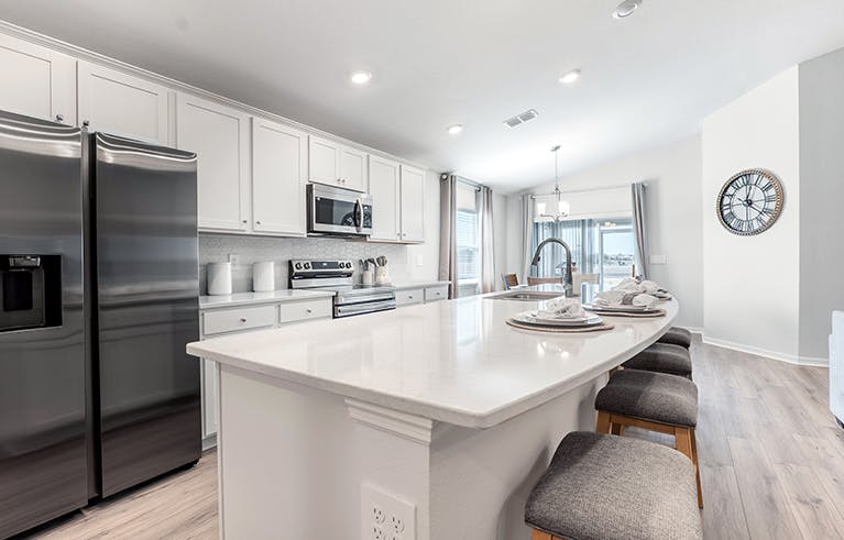 A bright, open kitchen with white cabinets and a large island, in a Lakeland, Florida, new construction home.