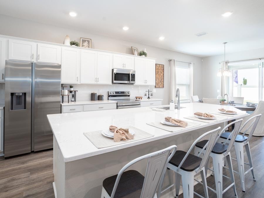 White cabinets, quartz, and rustic flooring create a timeless look in this Auburndale new home.