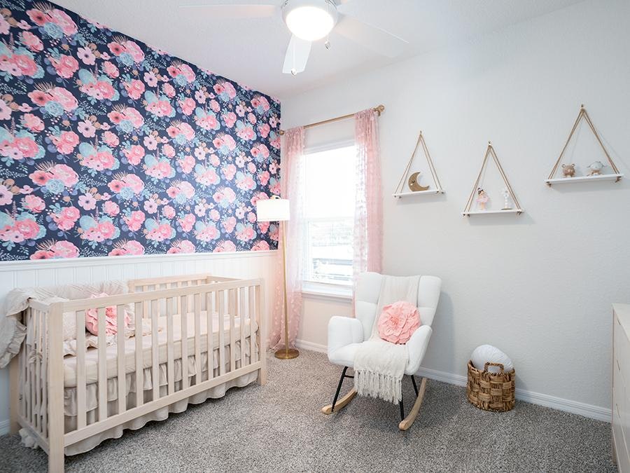 Nursery featuring a wallpapered accent wall